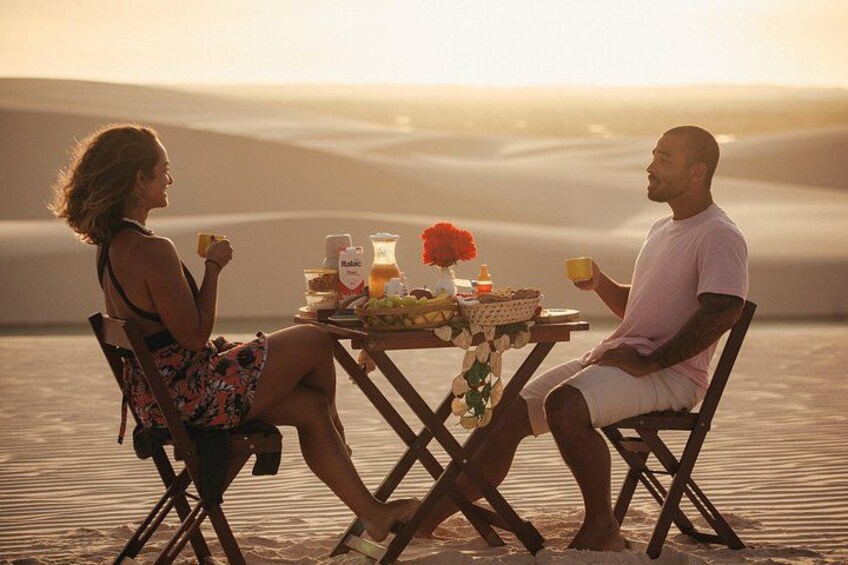 Two people sitting at a table with a meal, overlooking a desert landscape. 1