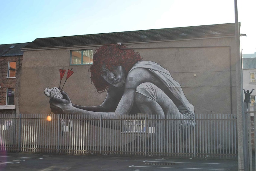 Une fresque représentant une personne tenant des flèches, peinte sur un mur d’immeuble. 2