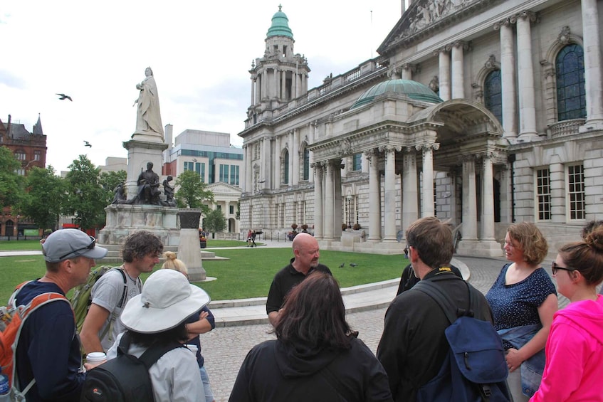Un groupe de personnes se tient devant un grand bâtiment historique à l’architecture classique, avec des colonnes et un dôme. 1