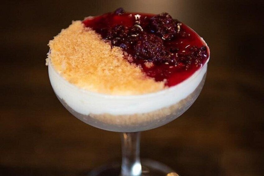 Un dessert servi dans un verre, composé d’une garniture croustillante et d’une compote de fruits rouges. 1