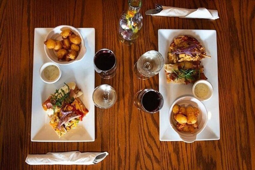 Deux assiettes carrées remplies de nourriture sont posées sur une table en bois, chacune accompagnée d’un petit bol de sauce et d’un verre d’eau. 5