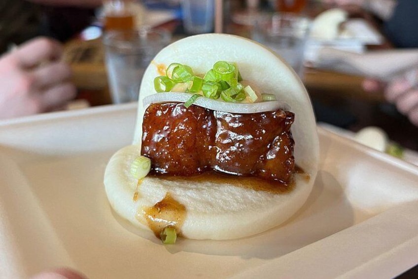 A food item with a bun, meat, and garnish. 5