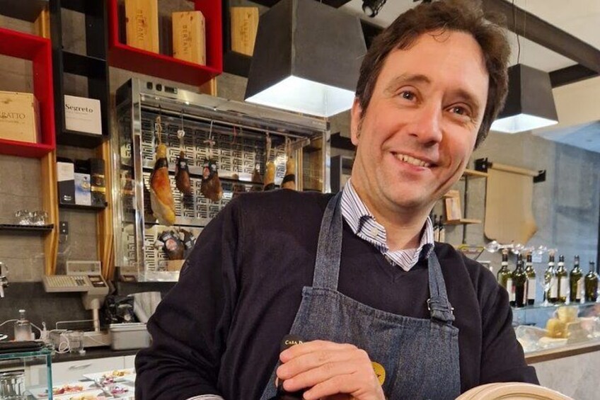 Una persona en una cocina con carnes colgadas y botellas de vino. 4