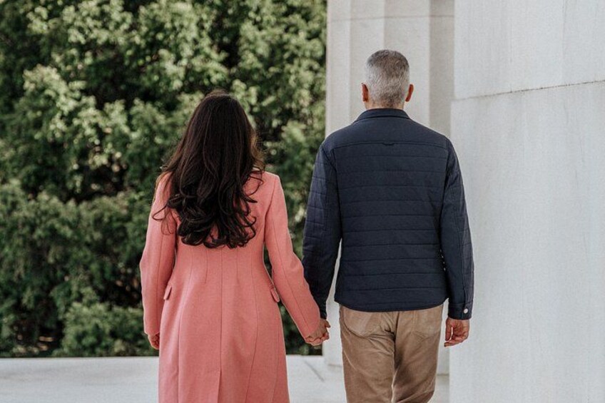 A couple walking on a path with a building and trees in the background. 5