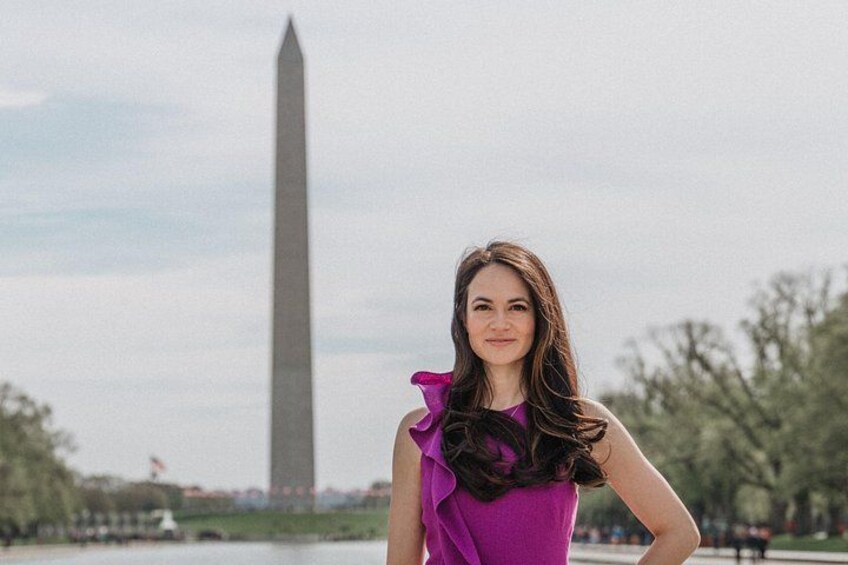 A person standing in front of the Washington Monument with trees and a body of water in the background. 3