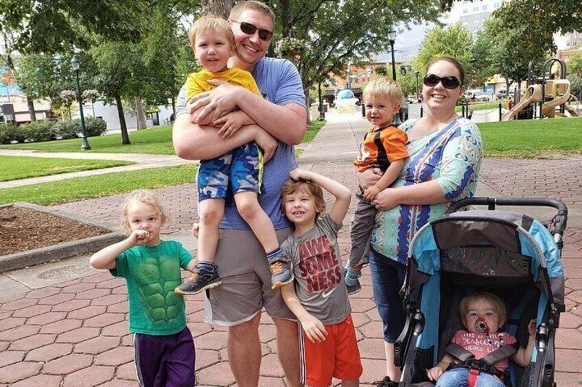 A family with children in a park with trees and a playground. 5