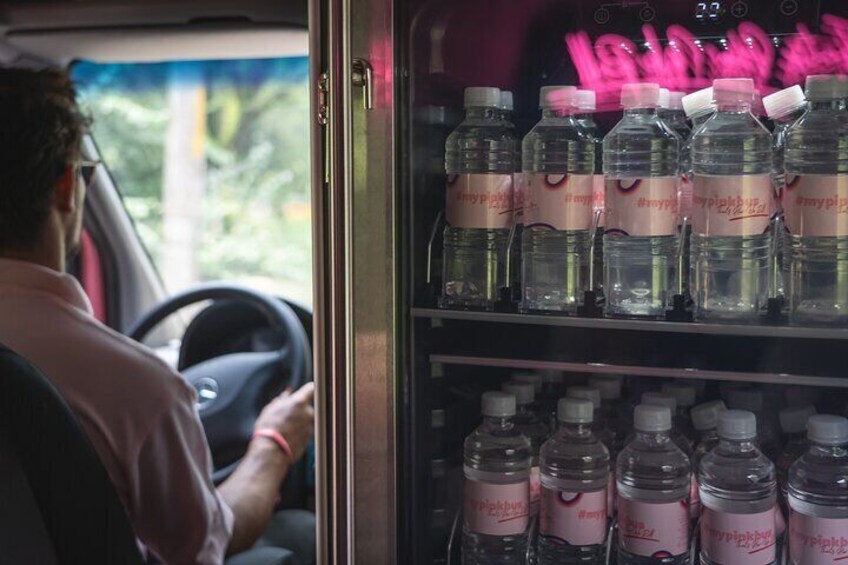 A man driving a vehicle with a water dispenser in the back. 3
