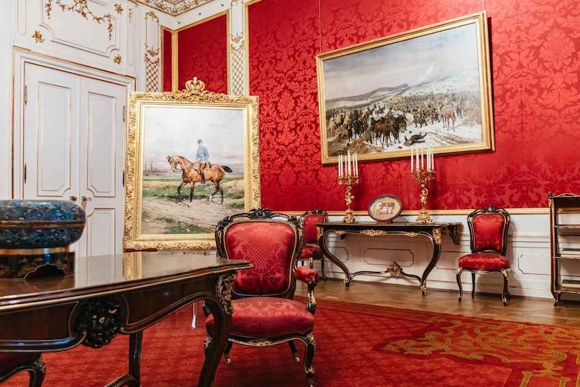 A room with red walls, ornate furniture, and a large painting of a horse. 3