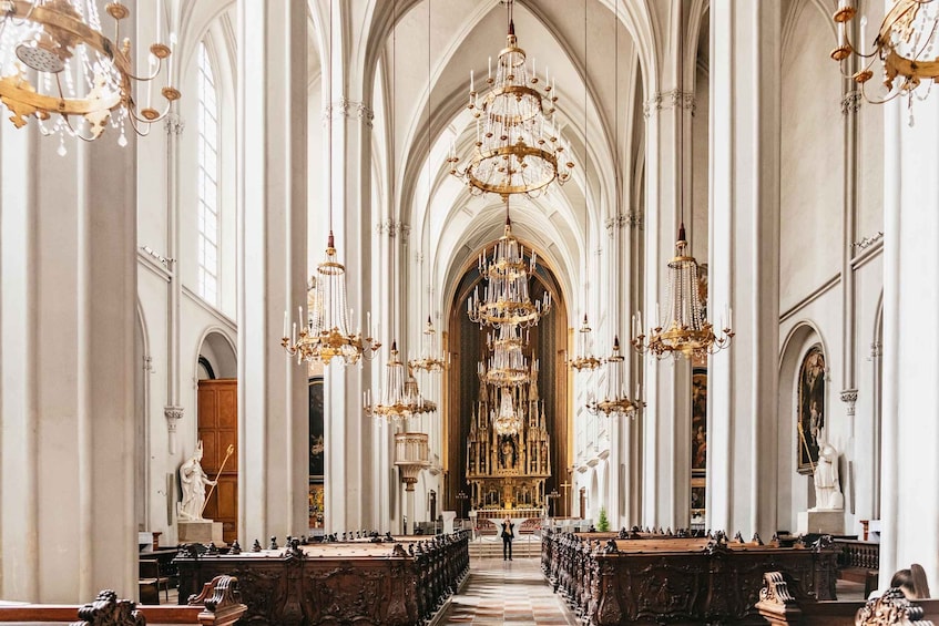 An ornate church interior with high ceilings, chandeliers, and a central altar. 4