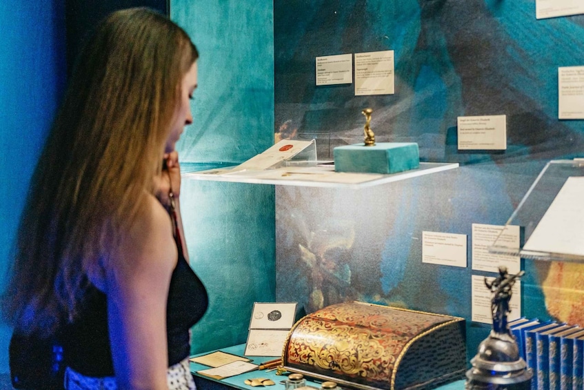 A museum exhibit with a display case containing a decorative box, a small statue, and informational plaques. 2