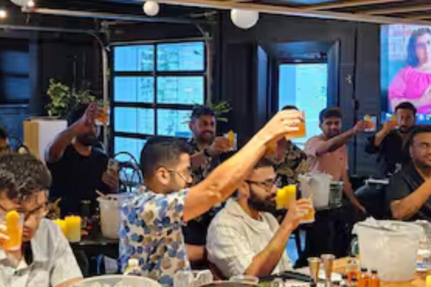 A group of people sitting at a table, some holding drinks. 1