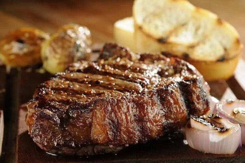 A grilled steak with onions and bread on a wooden board. 4