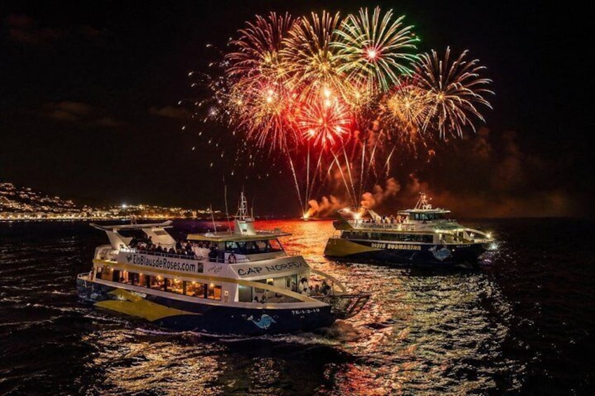 Two boats on a body of water with fireworks in the background. 1