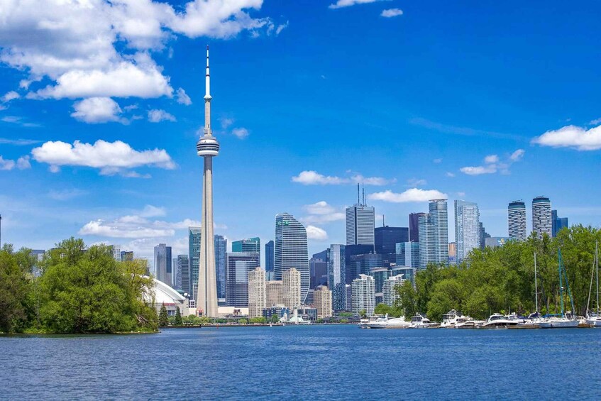 A city skyline with a prominent tower, modern buildings, and a waterfront with boats. 2