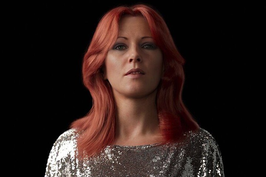Une personne aux cheveux roux, portant un haut brillant orné de paillettes. 2