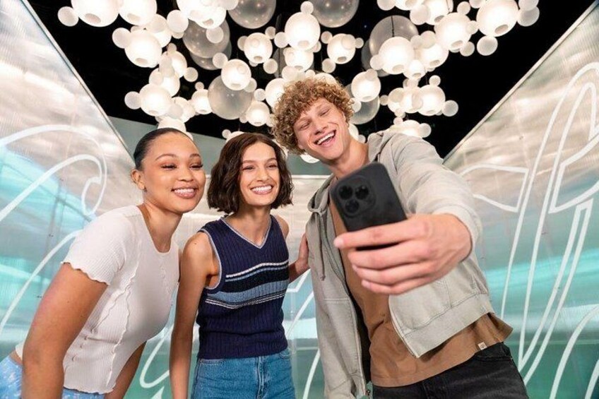 Tre persone si fanno un selfie con uno sfondo moderno illuminato. 2
