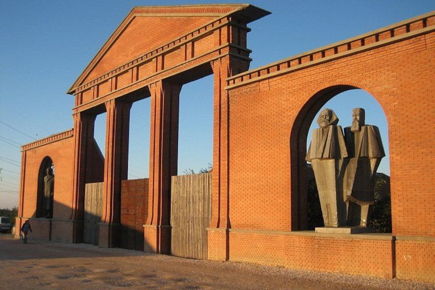 Een gebouw van baksteen met grote bogen en beelden. 1