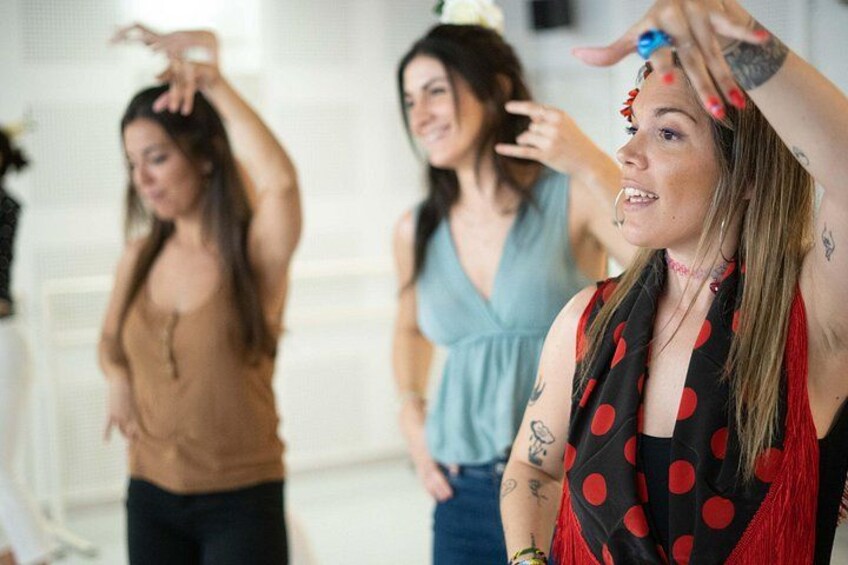 Trois femmes se trouvent dans une pièce : l’une a les cheveux roux et des tatouages, l’autre porte une robe bleue et la troisième est vêtue d’un haut marron. 2