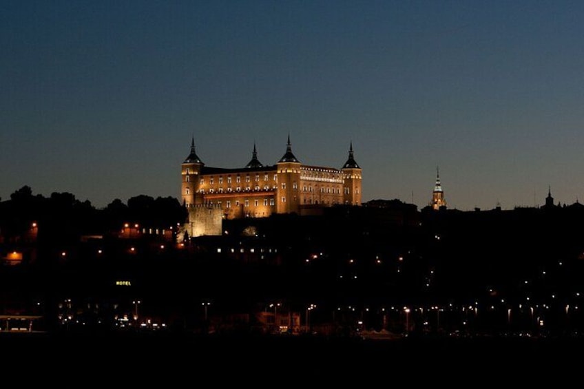Un château historique illuminé au crépuscule, avec de nombreuses tours, et entouré d’un paysage urbain. 2