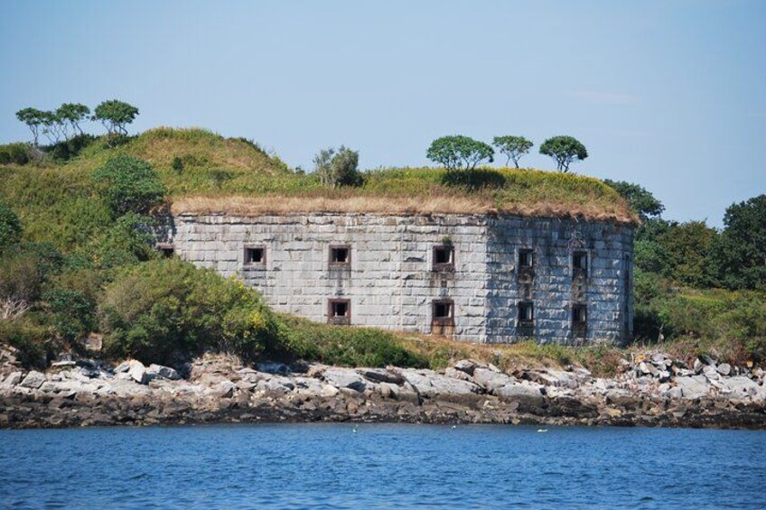 Un bâtiment en pierre, doté d’un toit de chaume, se dresse sur une côte rocheuse, entouré de verdure et d’arbres. 5