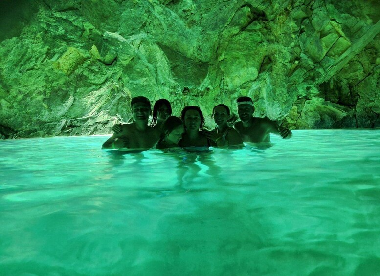 A group of people in a cave with turquoise water. 5