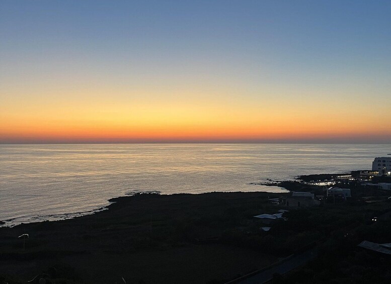 A coastal sunset with calm sea and buildings along the shore. 3