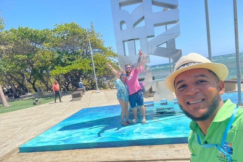 A pool with people standing on it, a large sign in the background, and a beach with trees. 5