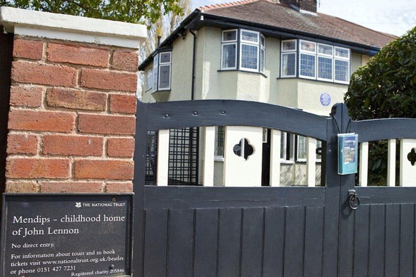 Une entrée fermée par un portail mène à une propriété où une plaque indique qu’il s’agit de la maison d’enfance de John Lennon, et où les lieux sont gérés par le National Trust. 2
