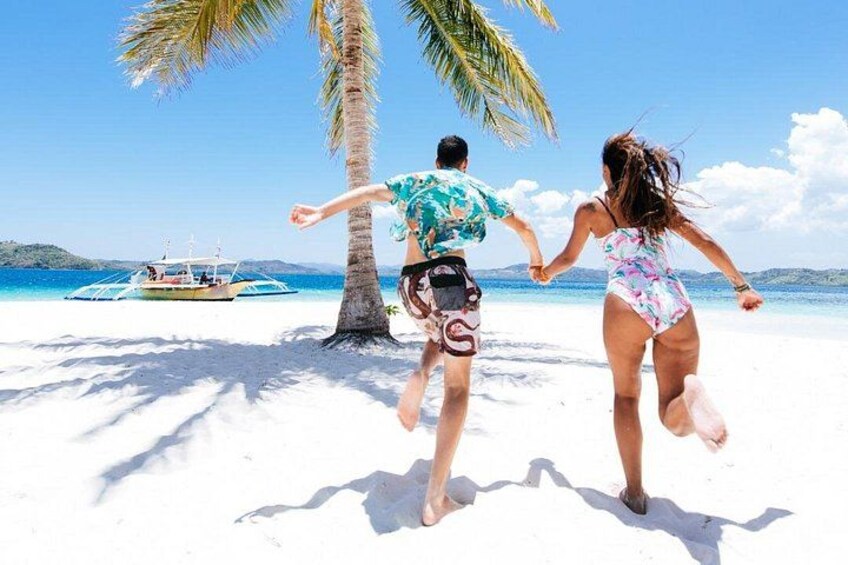 A couple running on a beach with a boat in the background. 3