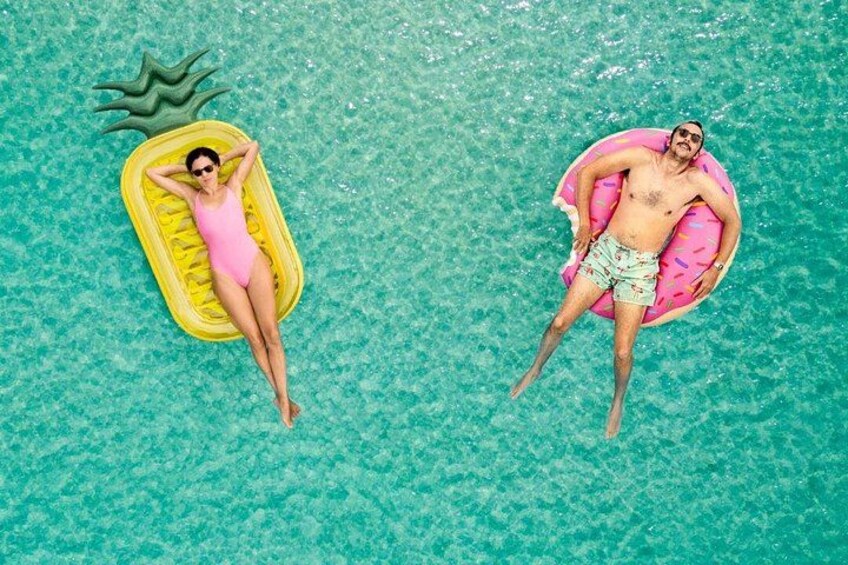 Two people lying on inflatable floats in a clear blue pool. 5