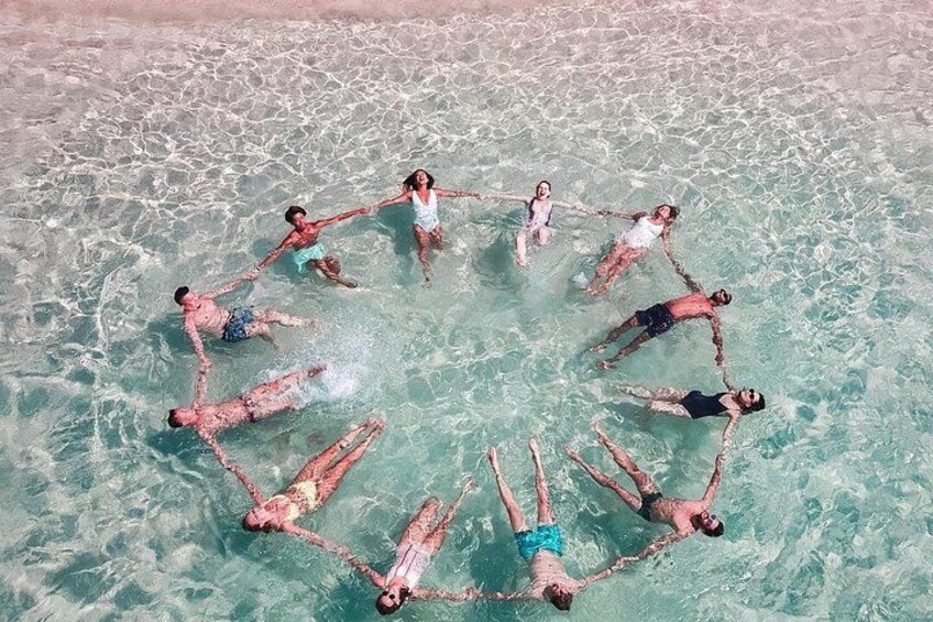 People forming a circle in the water at a beach. 1