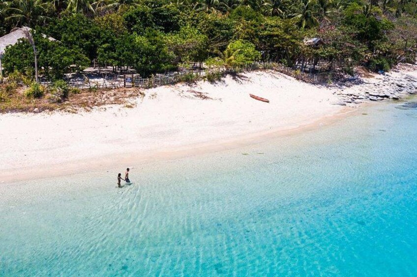 A beach with clear turquoise water, a sandy shore, and a few people walking. 4