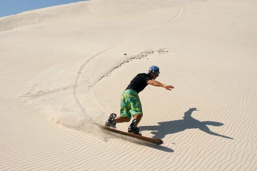 Una persona practica snowboard por una pendiente arenosa. 5