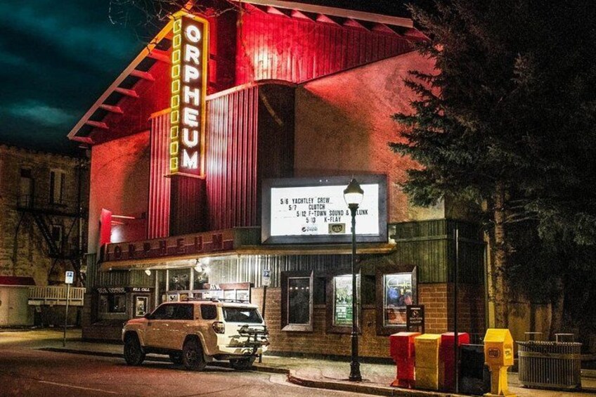 A theater with a marquee and a parked vehicle in front. 4