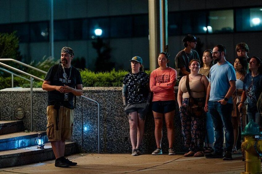 A group of people standing on a sidewalk at night. 2