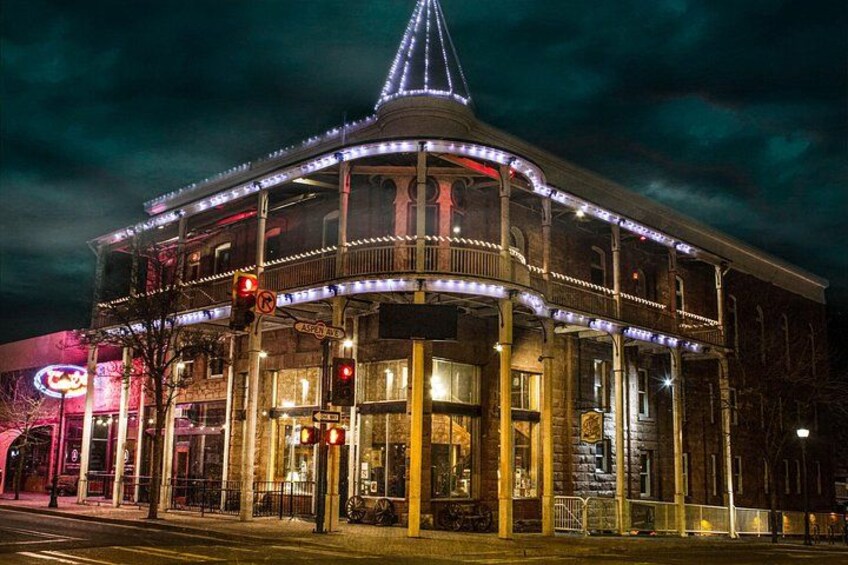 A historic building with a pointed roof and multiple balconies, illuminated by string lights. 1