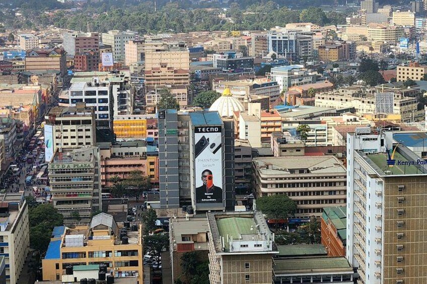 A cityscape with a prominent billboard featuring a man and the text 'TECHNO' and 'Kenya Power.' 3
