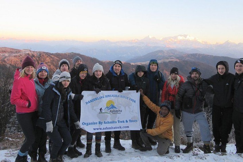 A group of people standing on a snowy mountain with a banner. 3