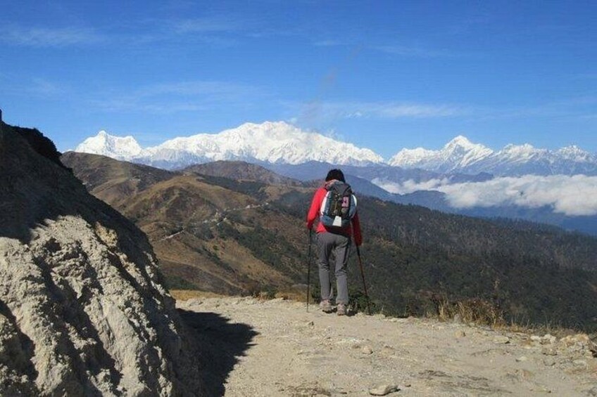 A hiker on a mountain trail with snow-capped peaks in the background. 4