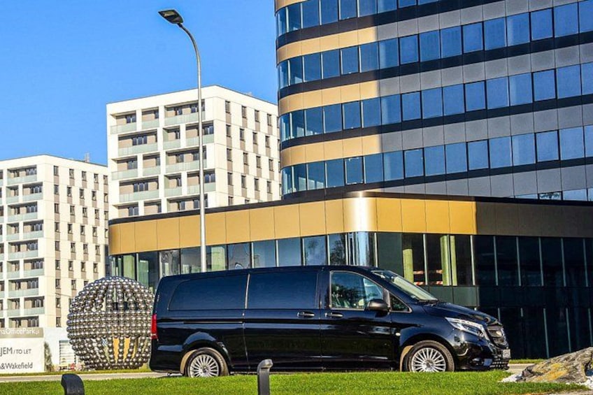 Un furgone nero parcheggiato di fronte a un edificio moderno, vicino a una scultura sferica. 5