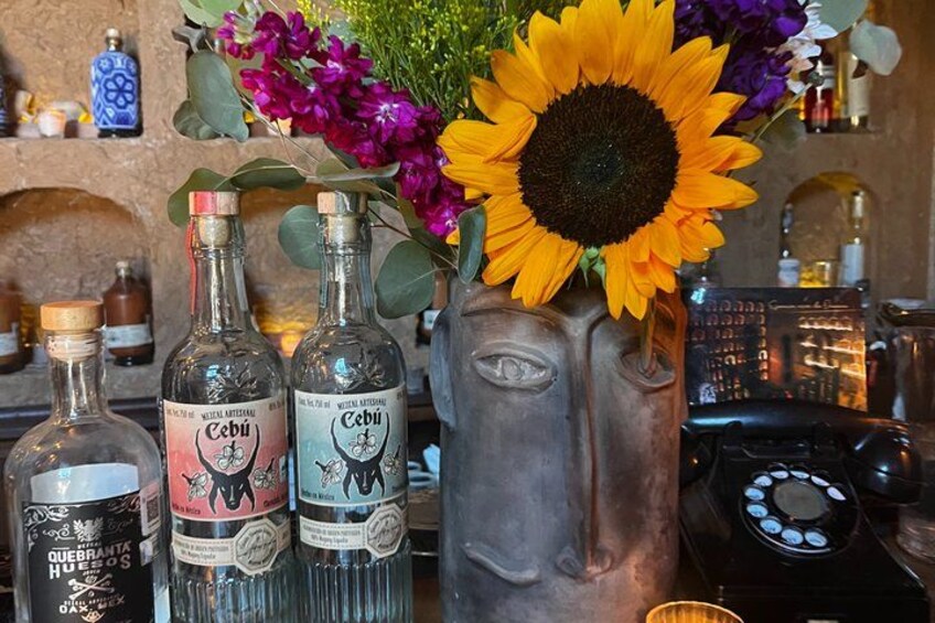 A bar setting with bottles, a vase with flowers, and a rotary phone. 4