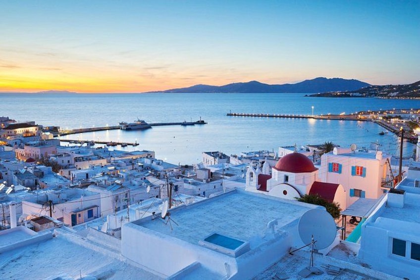 A coastal town with white buildings, a red-domed church, and a pier extending into the sea. 1