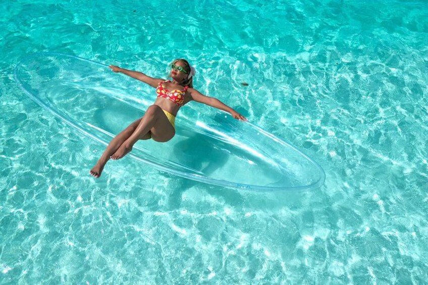 A person floating on a clear water surface with a transparent object. 2