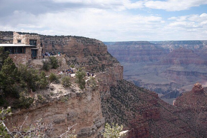 A canyon with a stone building and people on a viewing platform. 2