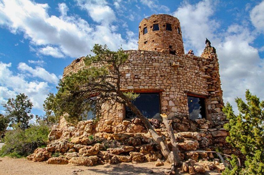 A stone tower with a circular top, surrounded by trees and rocks. 1