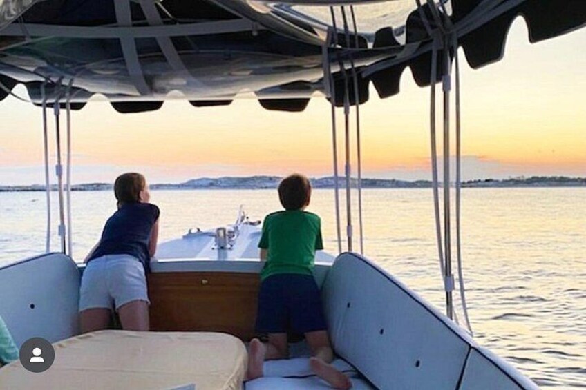 Dos personas en un bote, observando una puesta de sol sobre el agua. 3