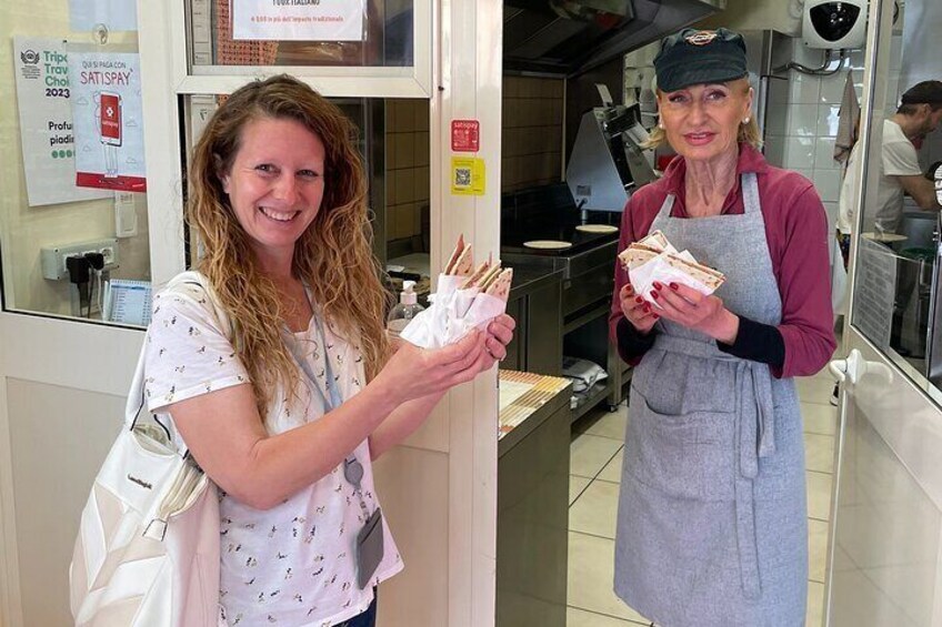 Twee personen houden belegde broodjes vast in een keuken. 1