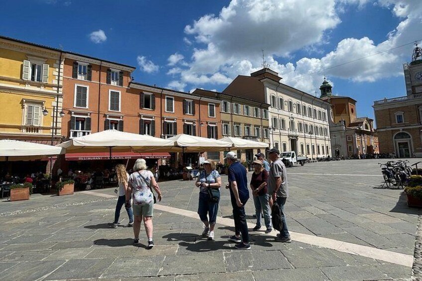 A square with people walking, historic buildings, and outdoor cafes. 5