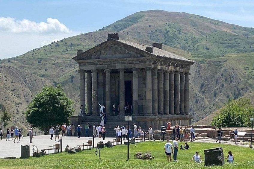 A classical building with columns, surrounded by a grassy area with people. 2