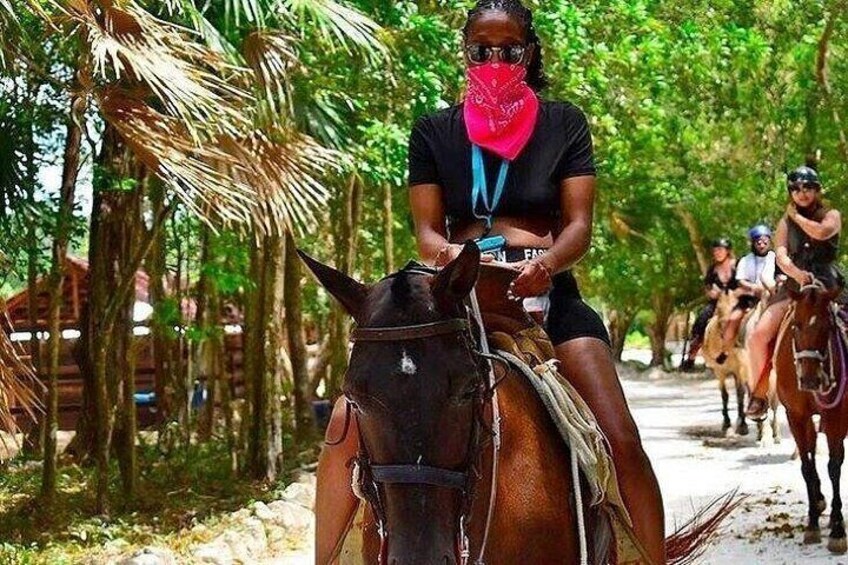 A person riding a horse on a dirt path surrounded by palm trees. 4